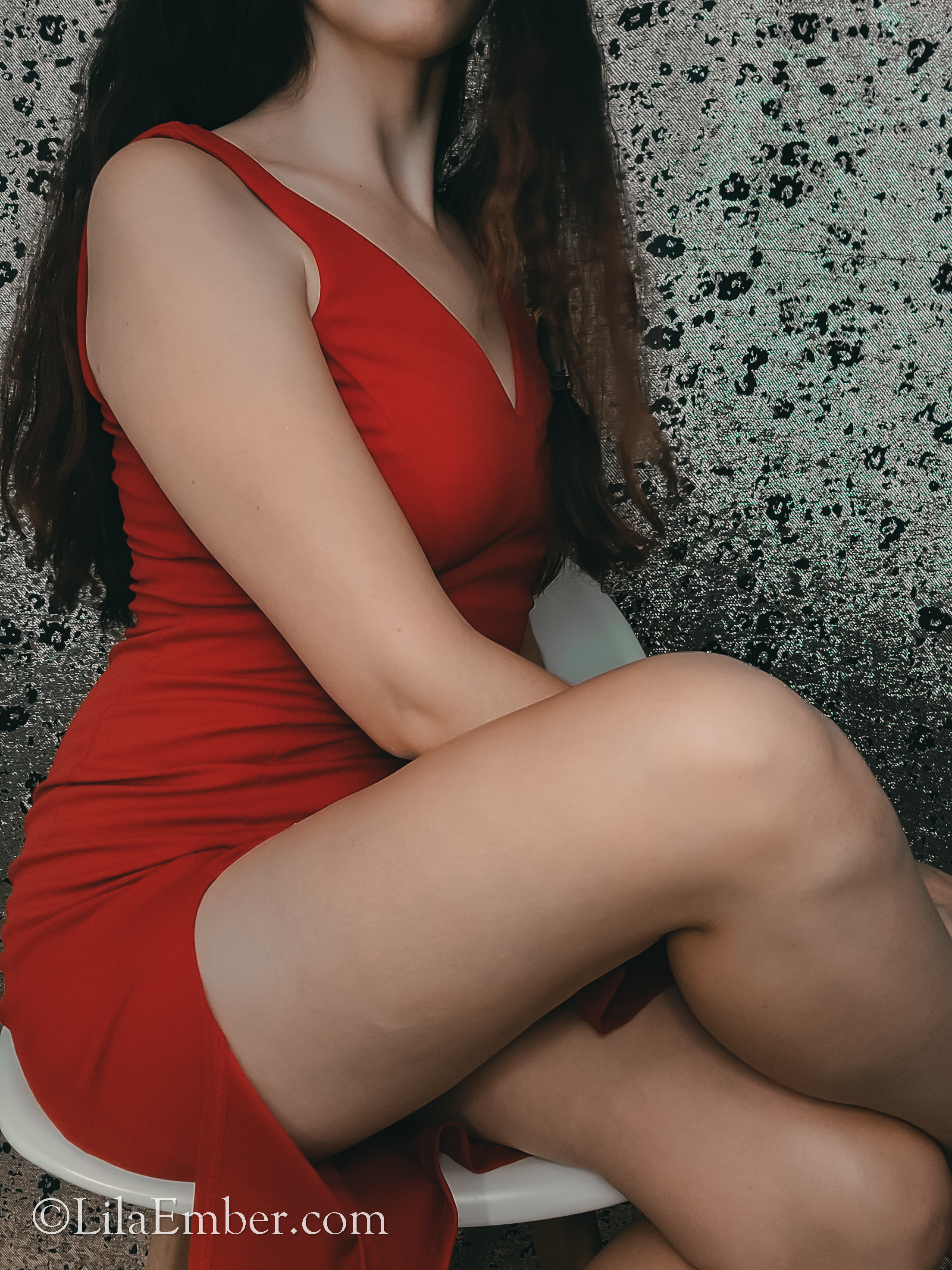 Woman sitting sophisticatedly in a sexy red dress.